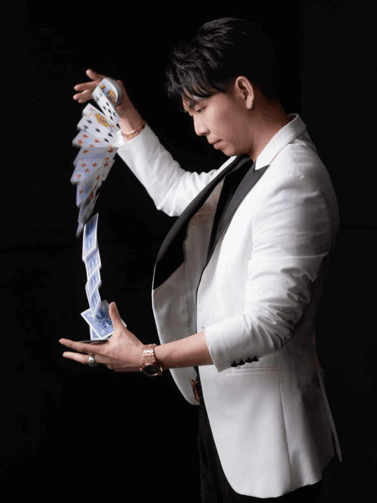 Magician in a white jacket producing a silk from his sleeve