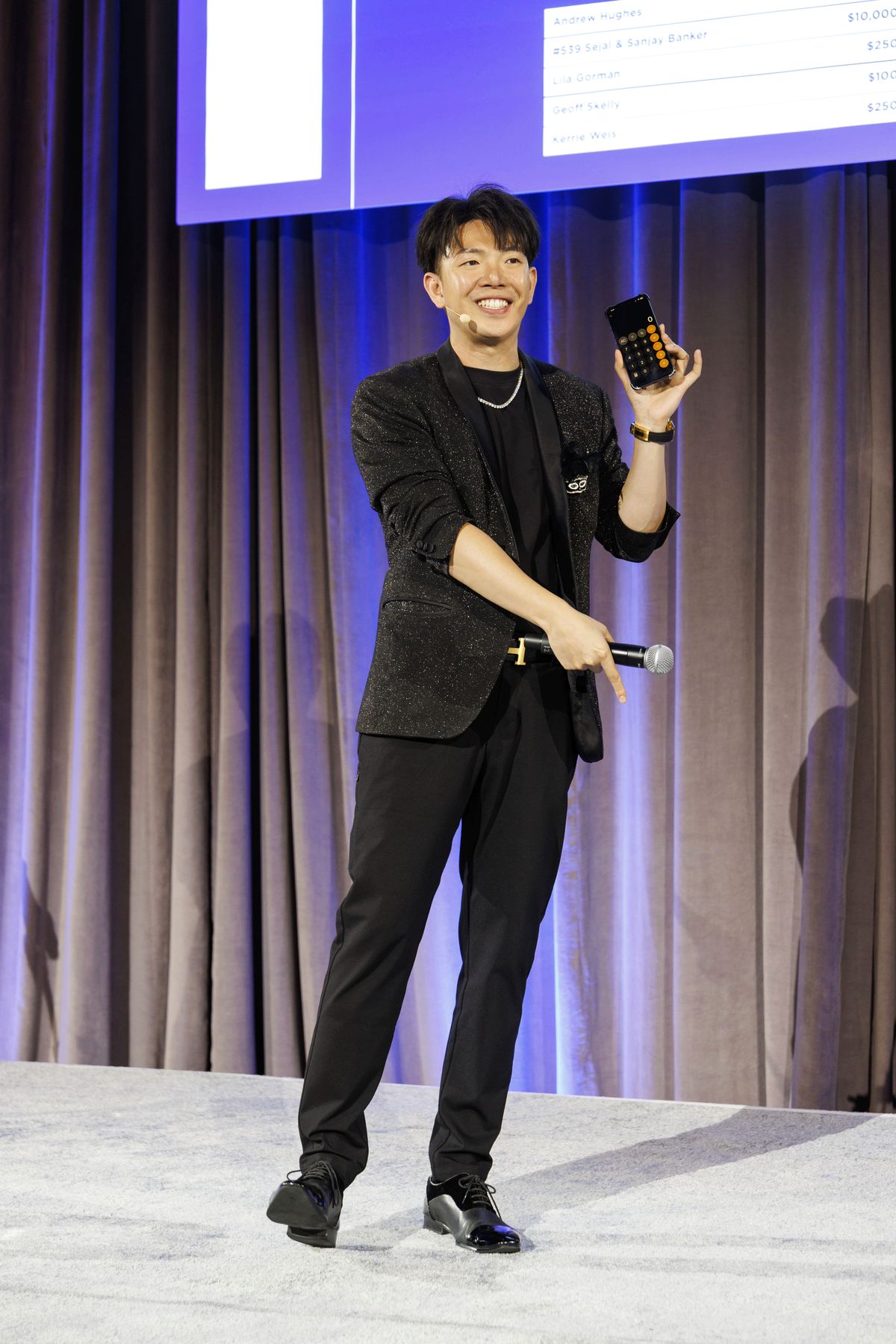 Johnny Wu revealing a prediction on a phone at a gala