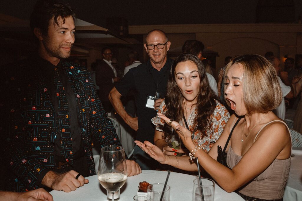 Guests gasp at a card trick by Omni Magic magician Dylan at a corporate conference by the beach