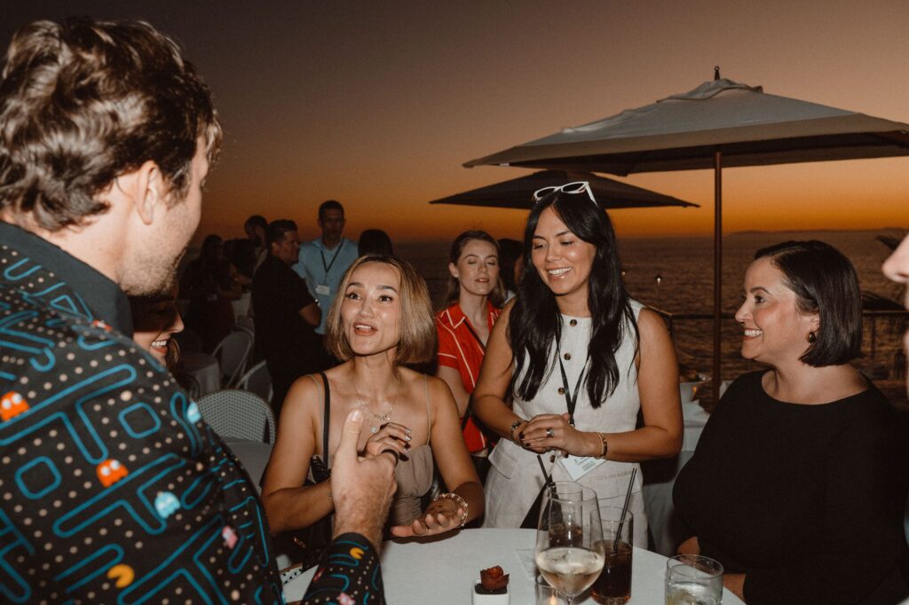 Guests laugh at sunset over the ocean during strolling magic by Omni Magic magician Dylan