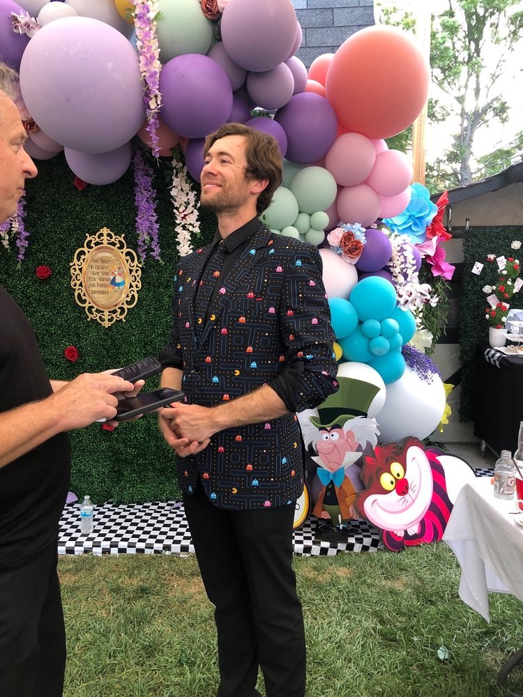 Dylan George performing at a backyard birthday party with balloons