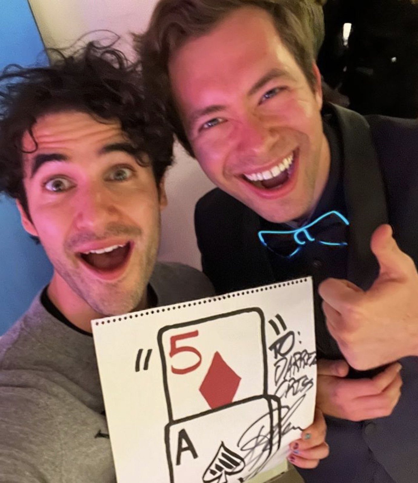 A guest holding up Dylan George's signed card prediction, five of diamonds