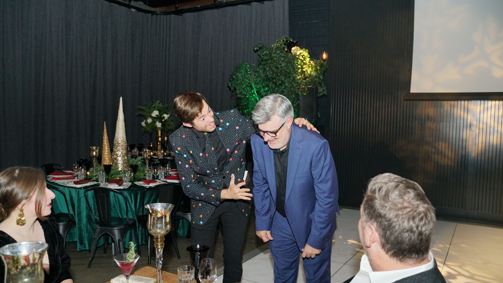 Dylan George performing for a seated guest at a corporate holiday party dinner table
