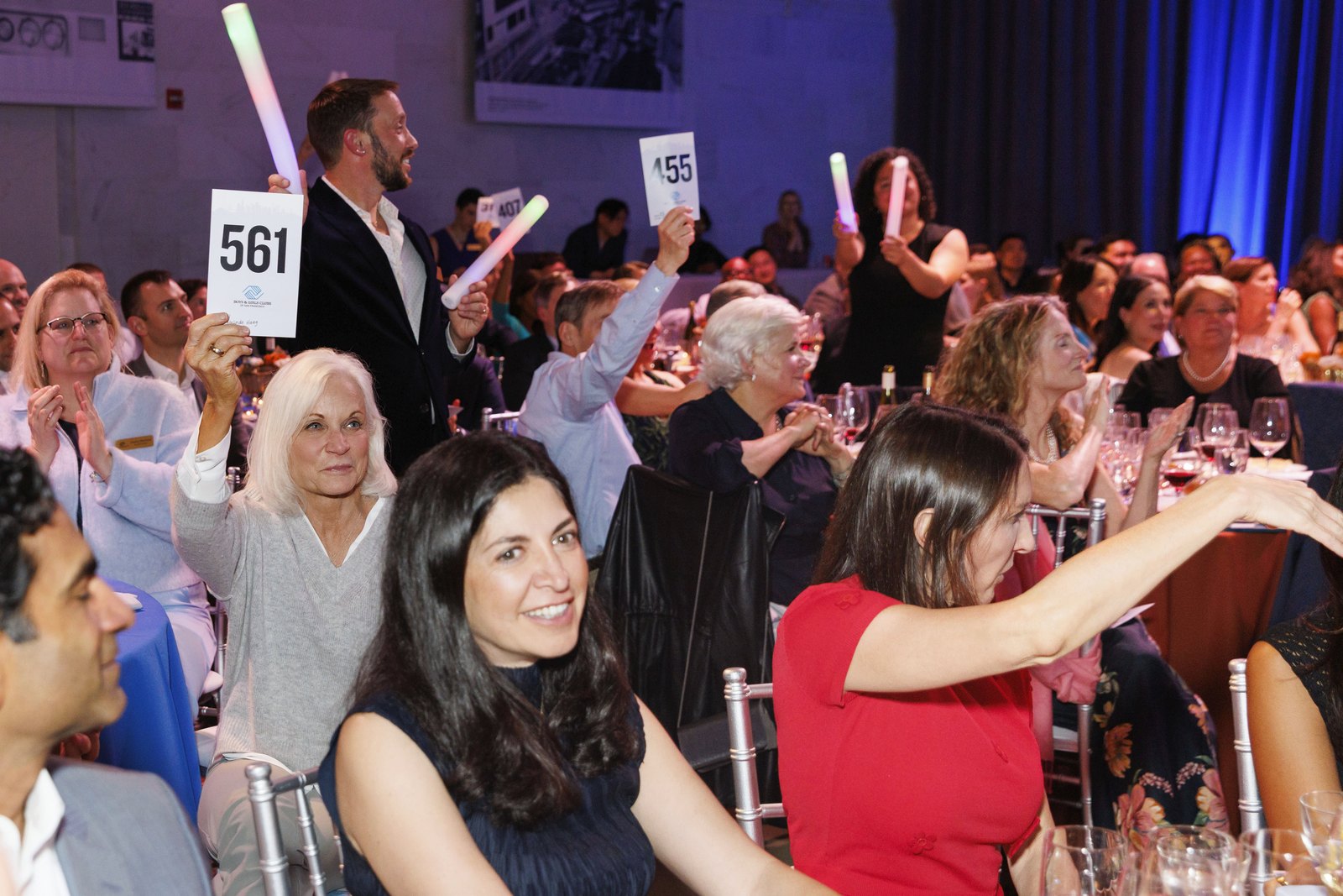A full gala room raising paddles and glow sticks during the fund-a-need