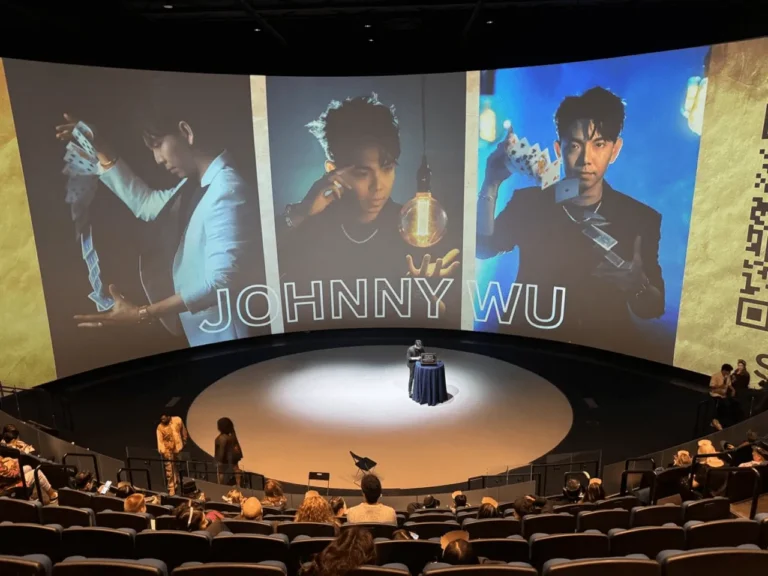 Johnny Wu performing on a large theater stage with video screens